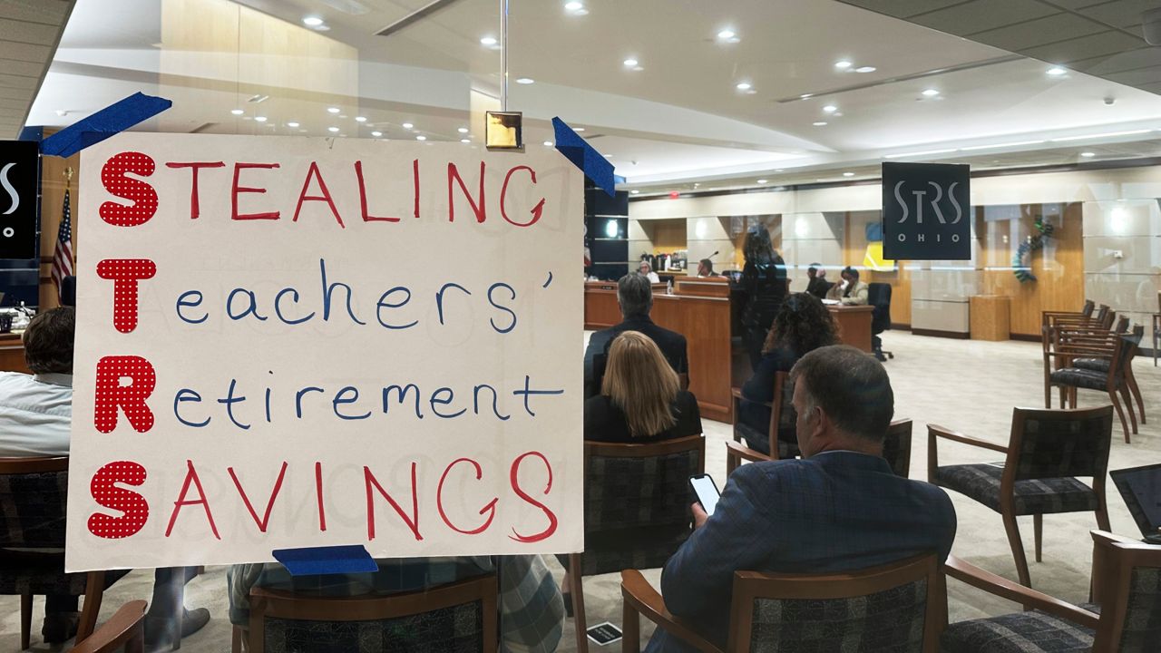 A poster using the initials of the State Teachers Retirement System of Ohio to spell out "Stealing Teachers' Retirement Savings" hangs on the wall during a board meeting at the pension fund's headquarters in Columbus, Ohio, on Wednesday, May 15, 2024.