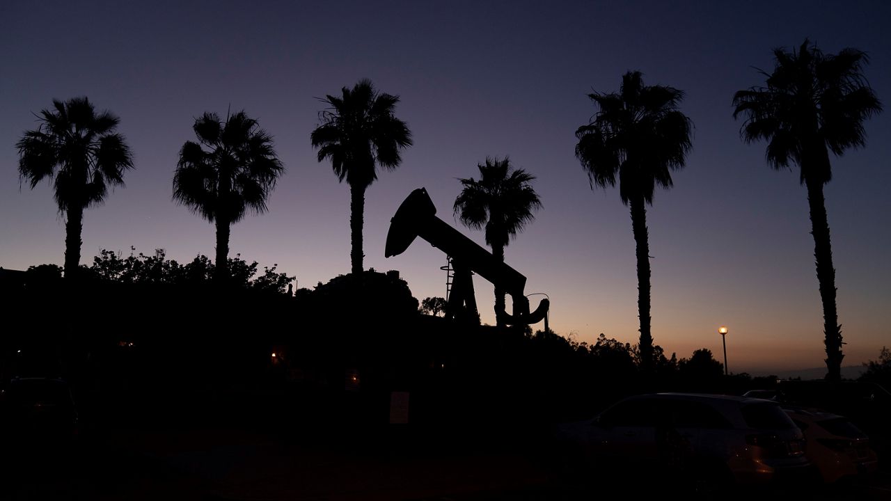 A pump jack sits idle in front of palm trees on June 9, 2021, in Signal Hill, Calif. (AP Photo/Jae C. Hong)