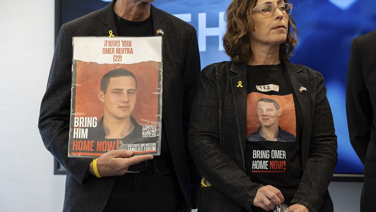 Ronen and Orna Neutra, parents of Israeli American hostage Omer Neutra, hold signs of their son during a news conference by families of American hostages in the Gaza Strip and elected officials, Friday, April. 5, 2024, in New York. (AP Photo/Yuki Iwamura)