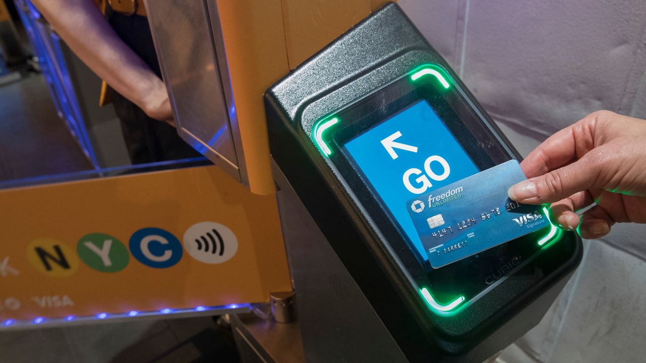 A representative from Visa demonstrates how a contactless card payment scanner installed at an MTA turnstile would work on Tuesday, May 21, 2019.