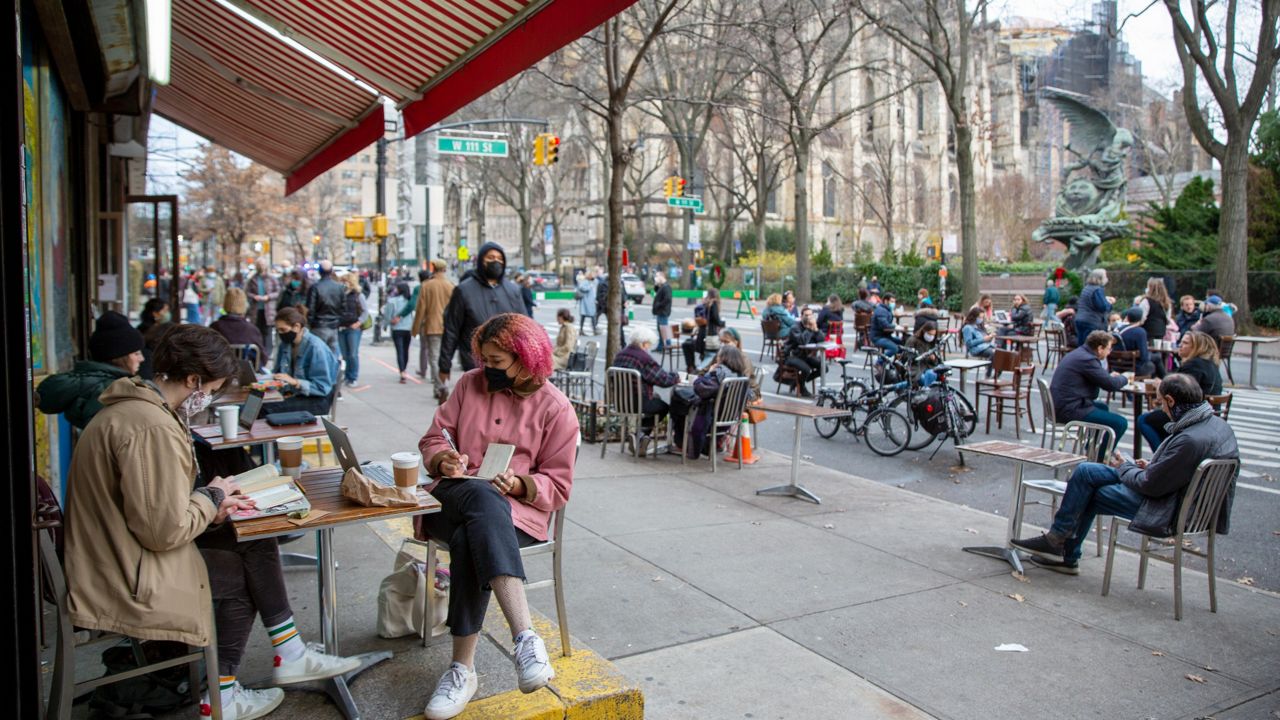 People eat at restaurant tables on a street block closed to vehicle traffic in Manhattan on Sunday, December 13, 2020.