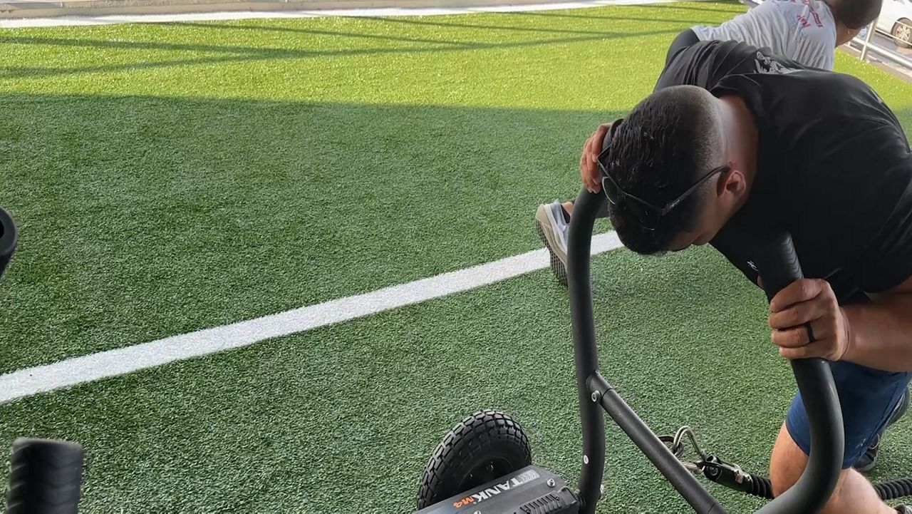 Rosmell Mejia Escobar pushes exercise equipment during workout. (Spectrum News)