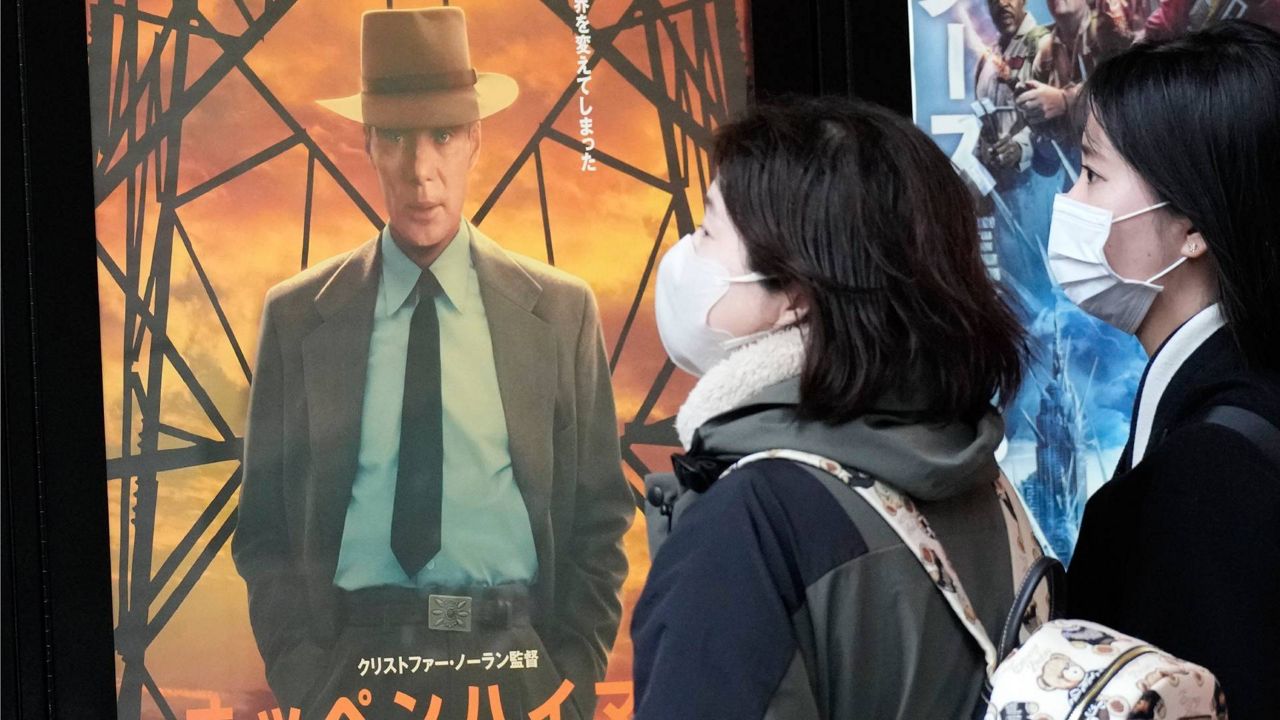 People walk by a poster to promote the movie "Oppenheimer" Friday in Tokyo. (AP Photo/Eugene Hoshiko)