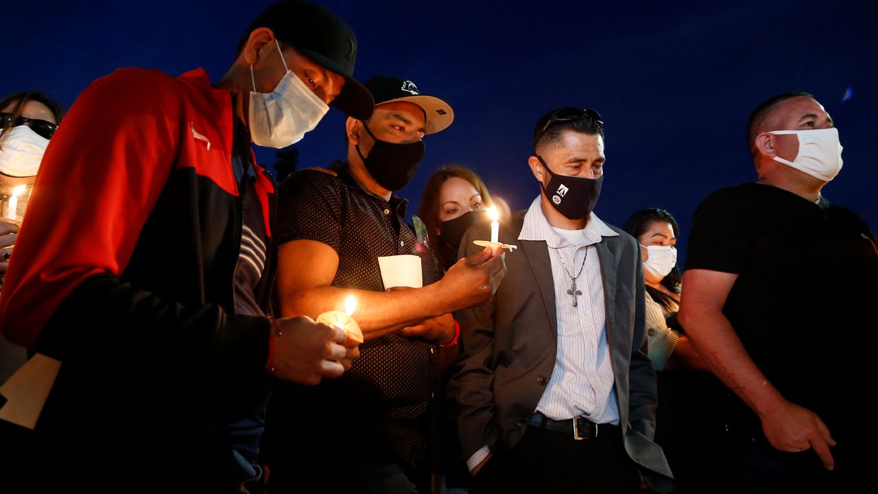 In a photo provided by Guillermo Lefranc, members of the community and family members hold a vigil outside the scene of a shooting in Orange, Calif., Sunday, April 4, 2021. (Guillermo Lefranc via AP)