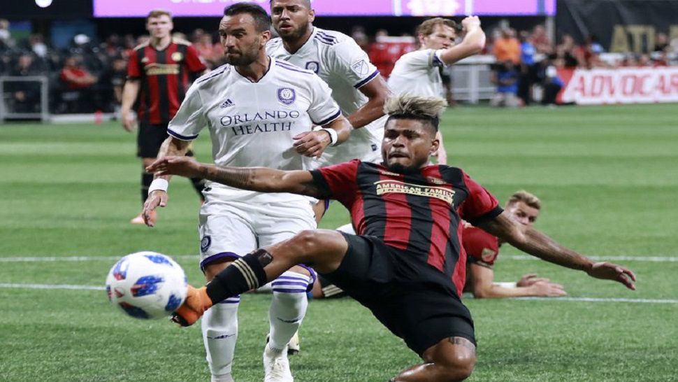 Atlanta United forward Josef Martinez, front right, shoots on goal past Orlando City defender Scott Sutter during the first half of an MLS soccer match Saturday, June 30, 2018, in Atlanta. (Curtis Compton/Atlanta Journal-Constitution via AP)