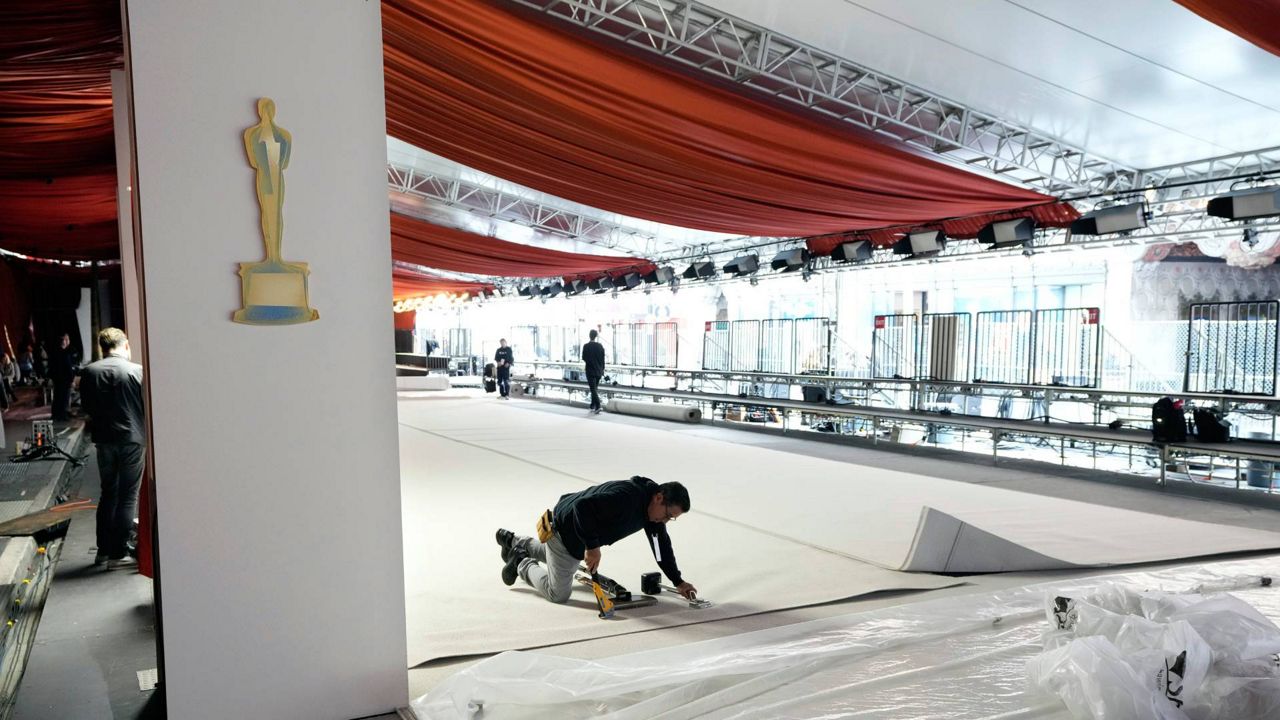 A crew member staples the carpet to the ground in preparation for Sunday's 95th Academy Awards on Wednesday outside the Dolby Theatre in Los Angeles. (AP Photo/Chris Pizzello)