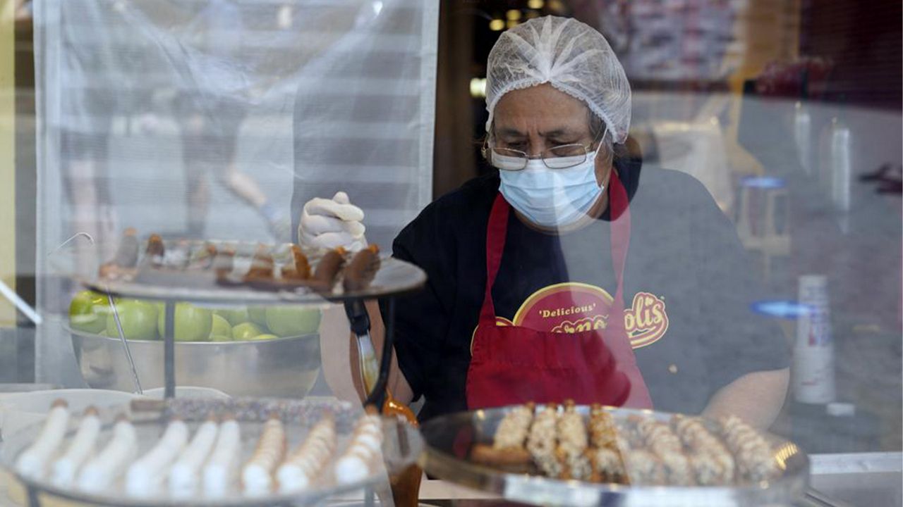 A worker wears a mask while preparing desserts at the Universal City Walk Friday, May 14, 2021, in Universal City, Calif. (AP Photo/Marcio Jose Sanchez, File)