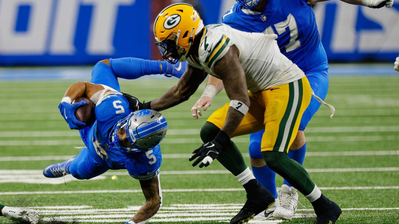 Detroit Lions running back David Montgomery (5) dives under Green Bay Packers linebacker Quay Walker