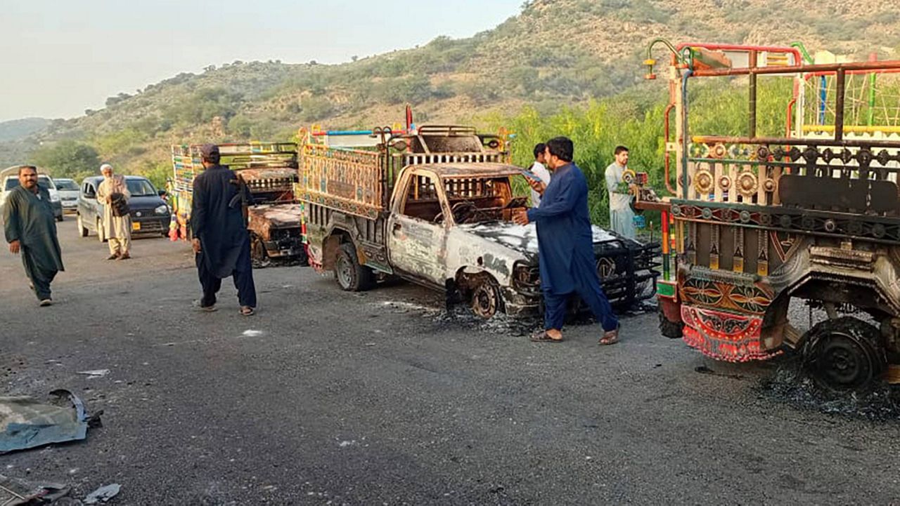 People look at burnt vehicles, torched by gunmen after killing passengers, at a highway in Musakhail, a district in Baluchistan province in southwestern Pakistan, Monday, Aug. 26, 2024. (AP Photo/Rahmat Khan)