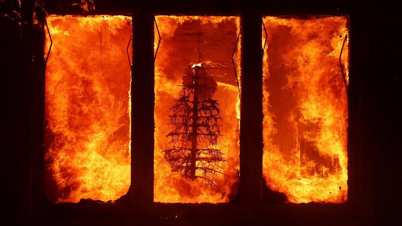 The Palisades Fire burns a Christmas tree inside a residence in the Pacific Palisades neighborhood of Los Angeles, Tuesday, Jan. 7, 2025. (AP Photo/Ethan Swope)