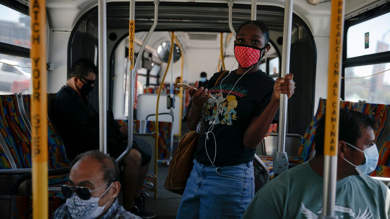 Commuters wearing masks ride a bus during the coronavirus pandemic in the Vermont Square neighborhood of Los Angeles, Thursday, May 21, 2020. (AP Photo/Jae C. Hong)