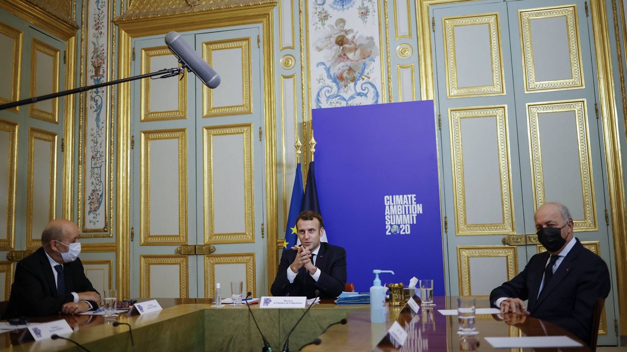 In this Dec. 12, 2020, file photo, French President Emmanuel Macron (center), flanked by French Foreign Minister Jean-Yves Le Drian (left) and President of the French Constitutional Council Laurent Fabius, speaks during the Climate Ambition Summit 2020 video conference at the Elysee Palace in Paris. (Yoan Valat, Pool via AP)  