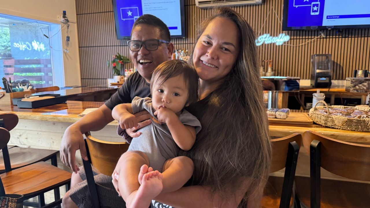 Addison Buloson hands off his son Zenith to his wife Nikki Cristobal on a recent weekday morning. The couple from Līhuʻe split child care responsibilities while working full-time jobs. The only place Bulosan said he can’t bring his son is County Council meetings. (Honolulu Civil Beat/Brittany Lyte)