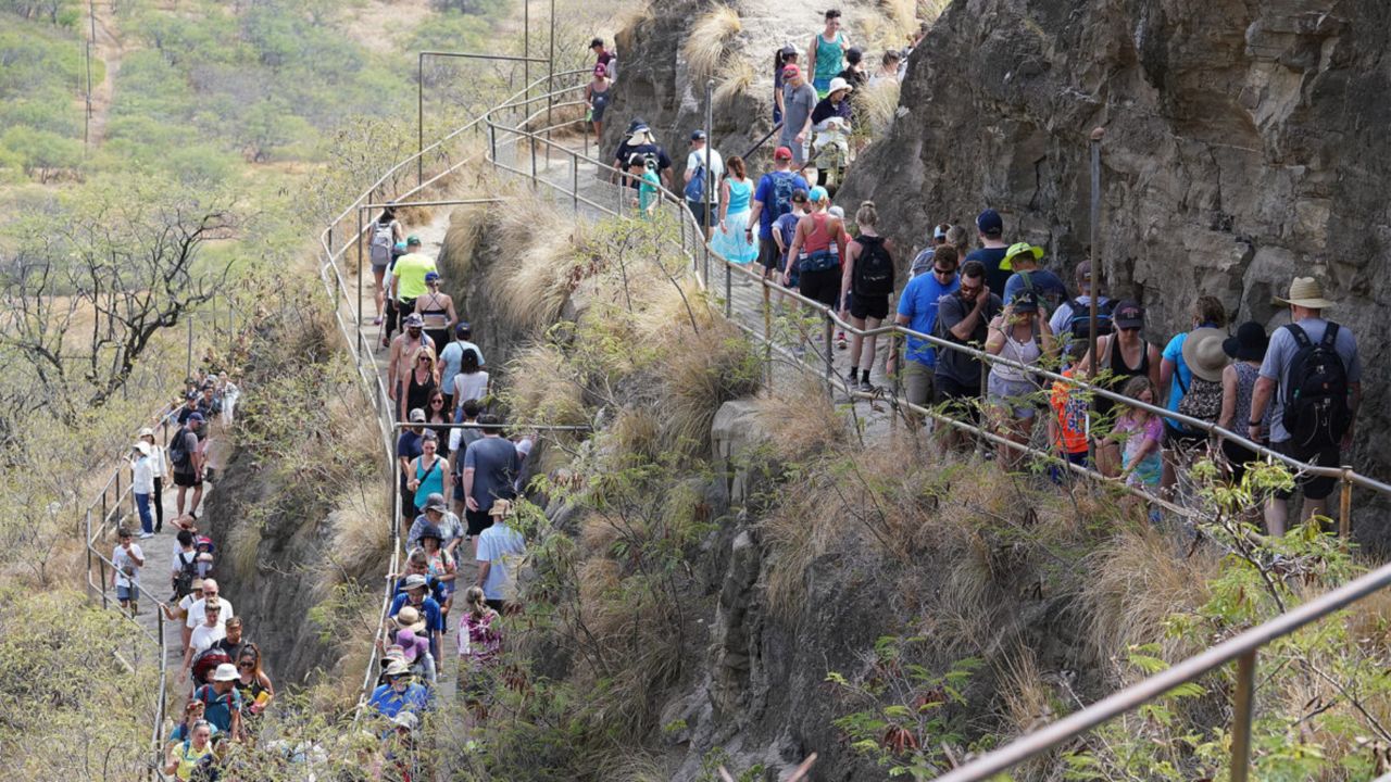 Surging tourist numbers, such as these hikers on Diamond Head in 2019, created a backlash among residents that led lawmakers to reconsider the role of the Hawaiʻi Tourism Authority as a marketing entity. (Honolulu Civil Beat/Cory Lum)