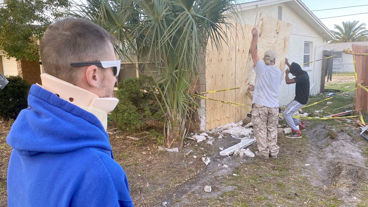 Mike Busby looks on as workers repair damage done to his home by a hit-and-run driver Sunday night. (Trevor Pettiford/Spectrum Bay New 9)