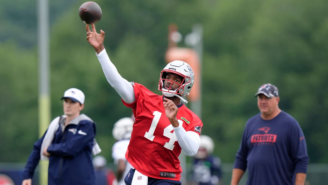 New England Patriots quarterback Jacoby Brissett (14) passes the ball in front of offensive coordinator Alex Van Pelt, right, during an NFL football training camp, Wednesday, July 24, 2024, in Foxborough, Mass. (AP Photo/Steven Senne)