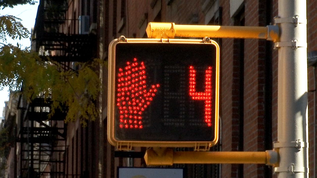 A crosswalk sign features a red hand and the numeral four, indicating there are only four seconds until the signal changes.