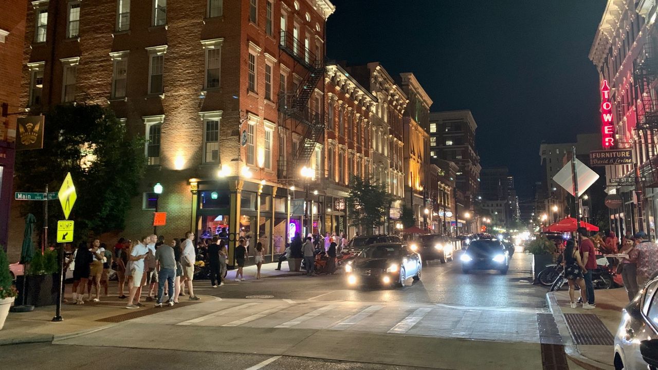 Night shot of pedestrians crossing road full of mopeds in busy