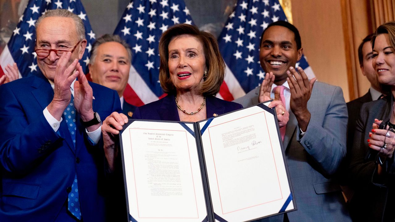 House Speaker Nancy Pelosi of Calif., accompanied by Senate Majority Leader Sen. Chuck Schumer of N.Y., left, and other members of congress, displays after signing the H.R. 8404, the Respect For Marriage Act, on Capitol Hill in Washington, Thursday, Dec. 8, 2022. (AP Photo/Andrew Harnik)