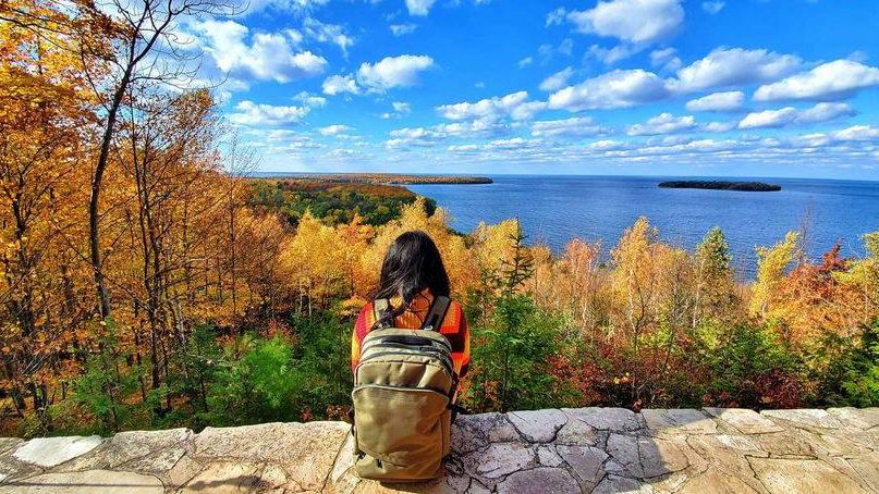 Hiker sits on a brick wall looking at fall foliage