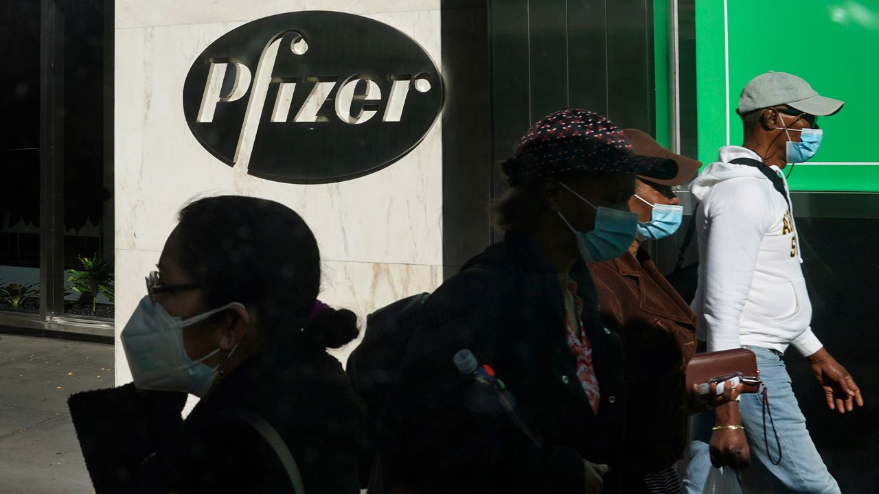 In this Nov. 9, 2020, file photo, pedestrians walk past Pfizer world headquarters in New York. (AP Photo/Bebeto Matthews, File)