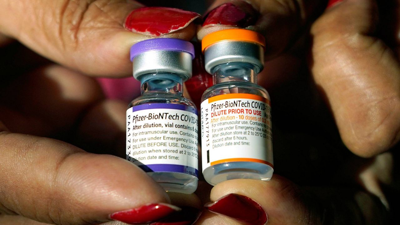 A nurse holds a vial of the Pfizer COVID-19 vaccine for children ages 5 to 11, right, and a vial of the vaccine for adults, which has a different colored label, at a vaccination station in Jackson, Miss. (AP Photo/Rogelio V. Solis, File)