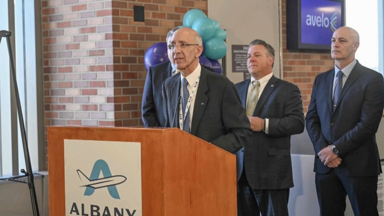 phil calderone speaks at an albany airport podium