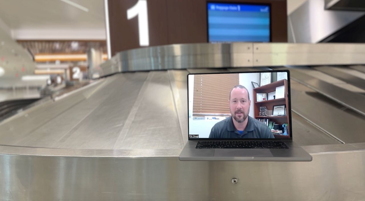 laptop sitting on airport luggage conveyor belt, with man speaking on video chat app in laptop