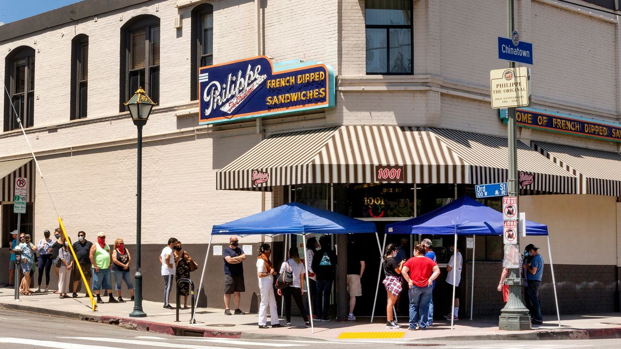 FILE - In this Saturday, May 2, 2020 file photo people stand in line while following social distancing guidelines as they wait for French dip sandwiches outside Philippe the Original restaurant in downtown Los Angeles. California restaurants have drafted recommendations to allow the industry to reopen for sit-down dining but with an array of safeguards, but would avoid setting percentage limits on occupancy or screening the temperature of patrons coming through the door. (AP Photo/Damian Dovarganes,File)