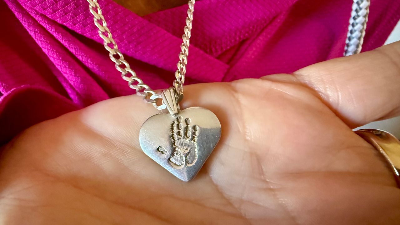 Linda Boyd’s necklace that is etched with a hand print of her late husband. (Spectrum News/Erin Murray)
