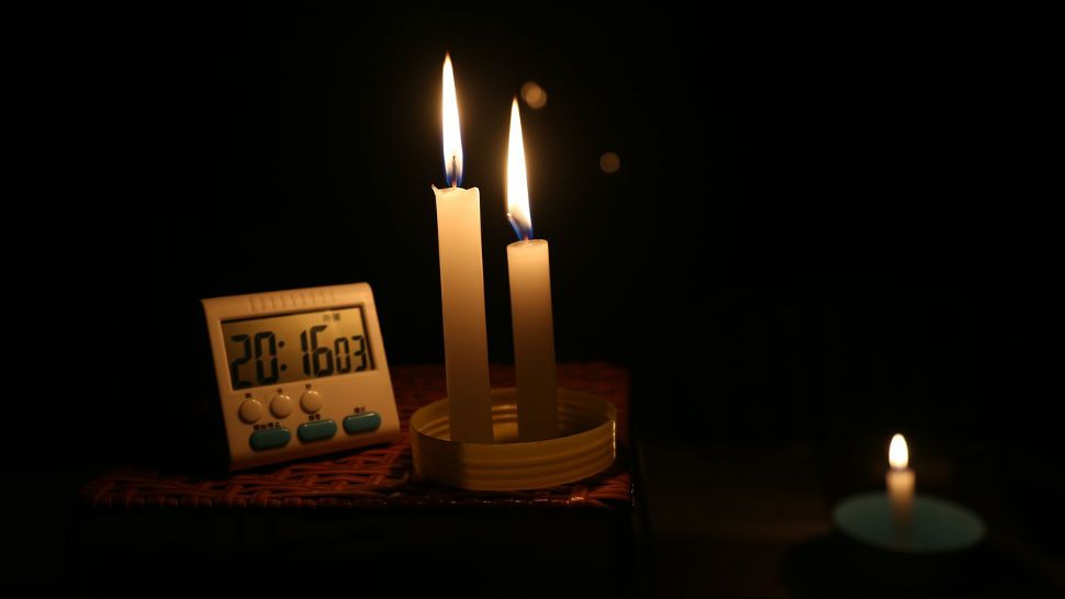 Two candles light up a digital clock. (Spectrum News/File)