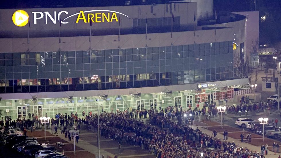 A large crowd waits to get into Carter-Finley Stadium for an NHL hockey Stadium Series game between the Washington Capitals and the Carolina Hurricanes, Saturday, Feb. 18, 2023, in Raleigh, N.C. Behind them is PNC Arena, where the Carolina Hurricanes play their home games. The Carolina Hurricanes have extended the lease at their home arena in Raleigh for 20 years through the 2043-44 NHL season. The extension announced Tuesday, Aug. 15, 2023, comes with major renovations to the building and development of the land around it into a dining and entertainment district with multi-family homes, a hotel and a separate music venue. (AP Photo/Chris Seward, File)