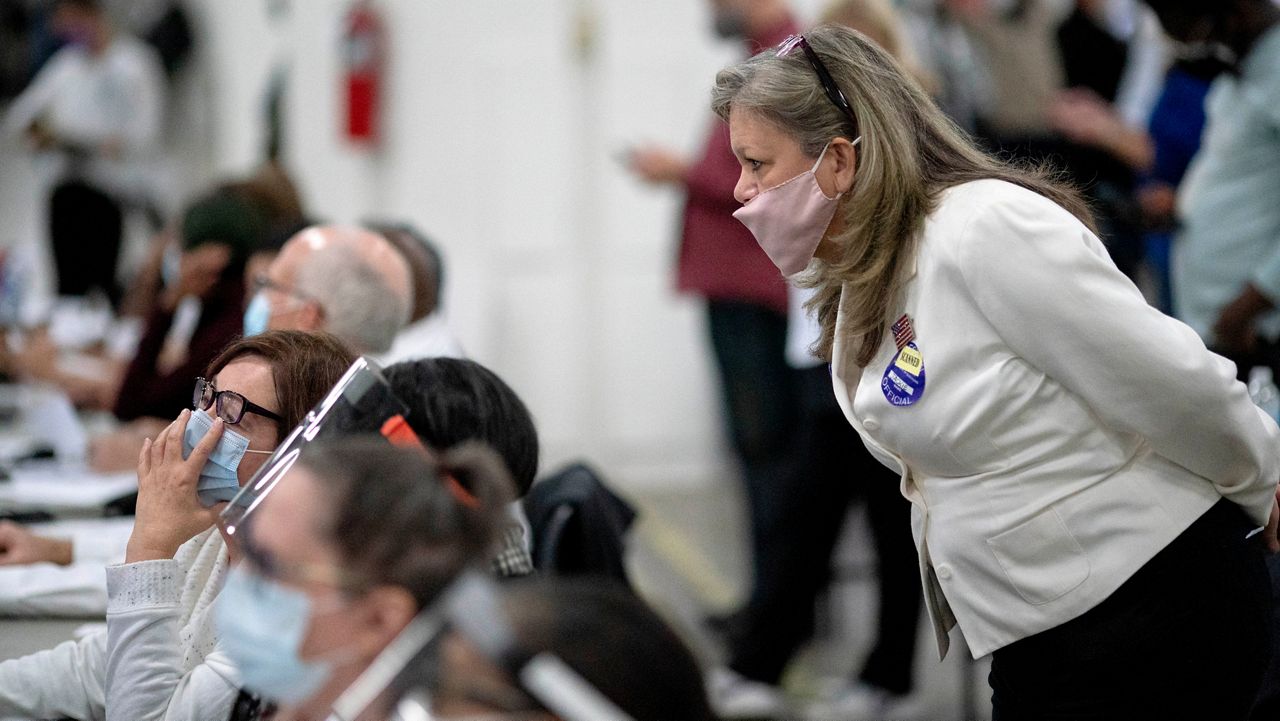 A Republican election challenger, right, watches over election inspectors as they examine a ballot Nov. 4, 2020, at the central counting board in Detroit. (AP Photo/David Goldman, File)