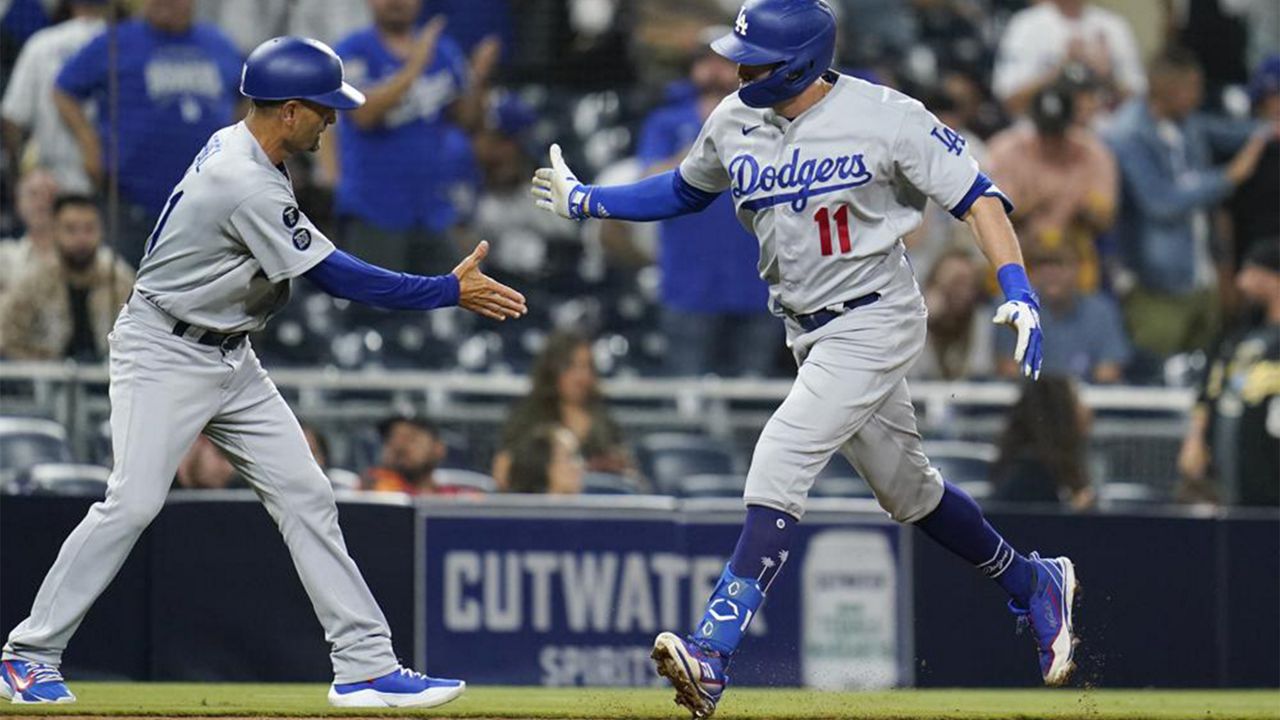 Los Angeles Dodgers' AJ Pollock, right, reacts with third base coach Dino Ebel after hitting a two-run home run during the sixteenth inning of a baseball game against the San Diego Padres, Thursday, Aug. 26, 2021, in San Diego. (AP Photo/Gregory Bull)