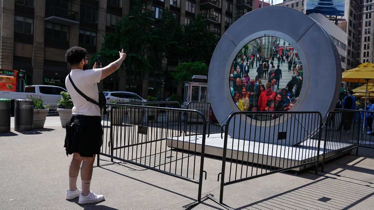 A man in New York City signals to pedestrians in Dublin through a livestream portal on Tuesday, May 14, 2024.