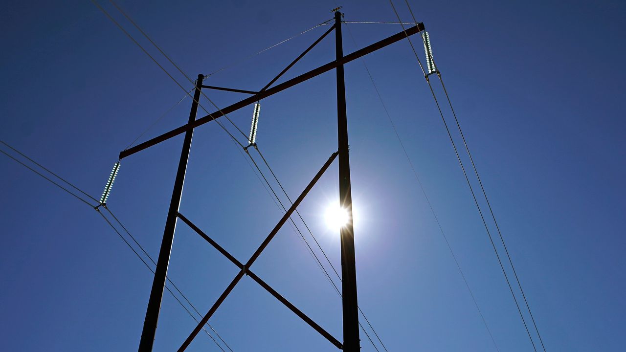 The sun shines through the towers of high voltage transmission lines, Tuesday, March 2, 2021, in Candia, N.H. (AP Photo/Charles Krupa)