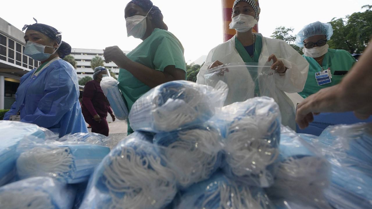 Healthcare workers line up for free personal protective equipment at Jackson Memorial Hospital, Sept. 22, 2020, in Miami. Hundreds of workers lined up for the PPE provided by the New York nonprofit Cut Red Tape 4 Heroes. (AP Photo/Wilfredo Lee)