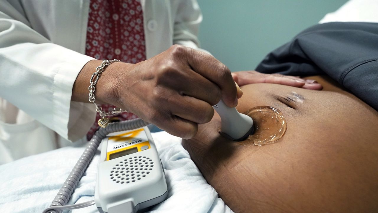 A doctor uses a handheld Doppler probe on a pregnant woman to measure the heartbeat of the fetus. (AP Photo/Rogelio V. Solis, File)
