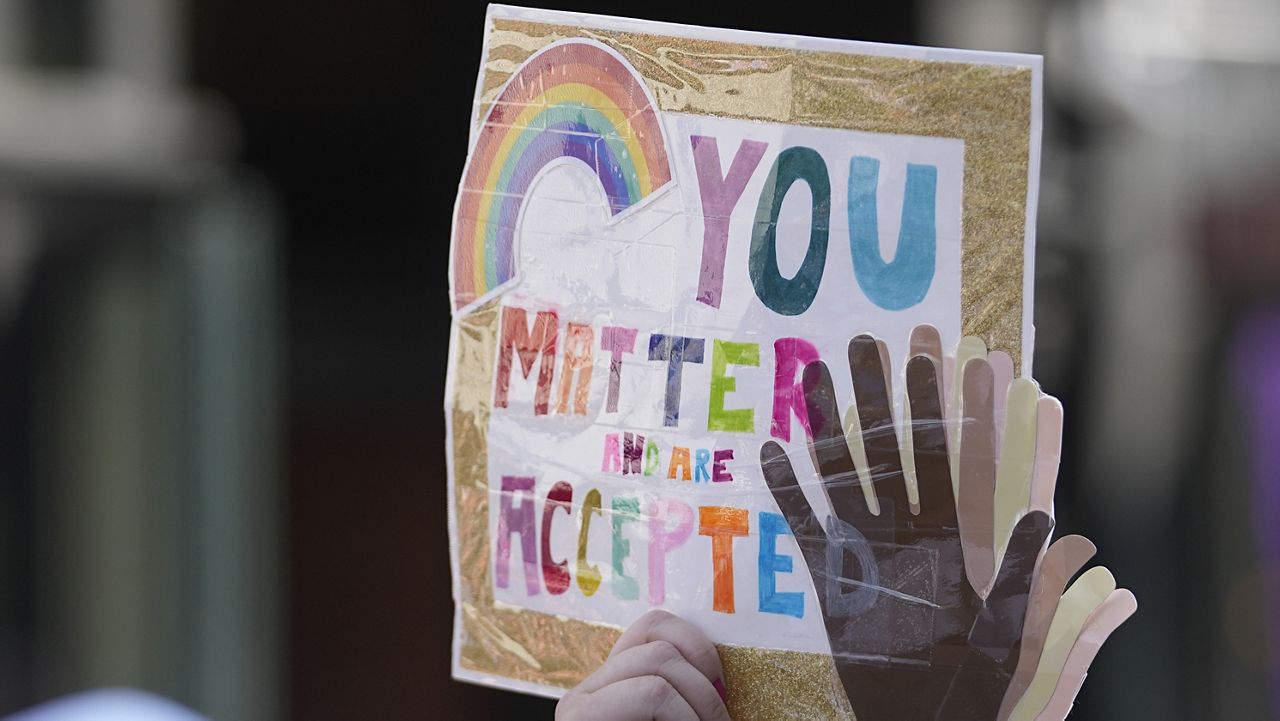 A participant holds up a sign while walking during a Pride parade, Saturday, June 10, 2023. (AP Photo/Darron Cummings)