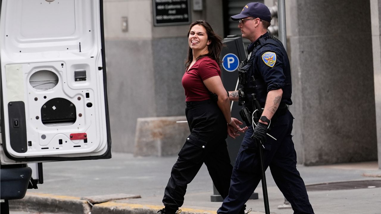 A pro-Palestinian demonstrator sticks her tongue out as she is escorted to a police vehicle outside a building housing the Israeli Consulate in San Francisco on Monday. (AP Photo/Jeff Chiu)