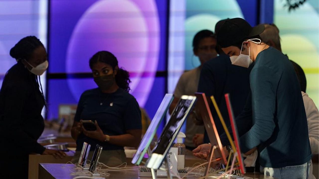 In this June 9, 2021, file photo, workers and customers wear masks inside an Apple Store amid the COVID-19 pandemic on The Promenade, in Santa Monica, Calif. (AP Photo/Marcio Jose Sanchez, File)