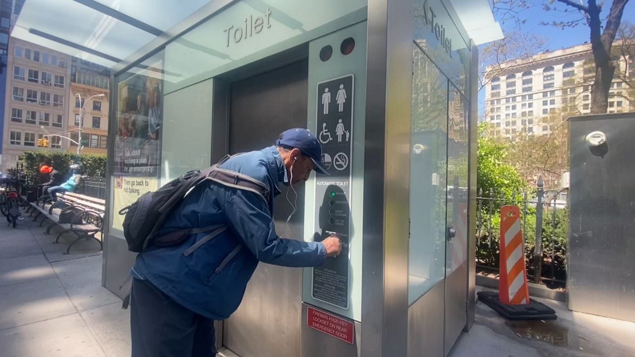 A man pushing a button for entry into a public toilet.