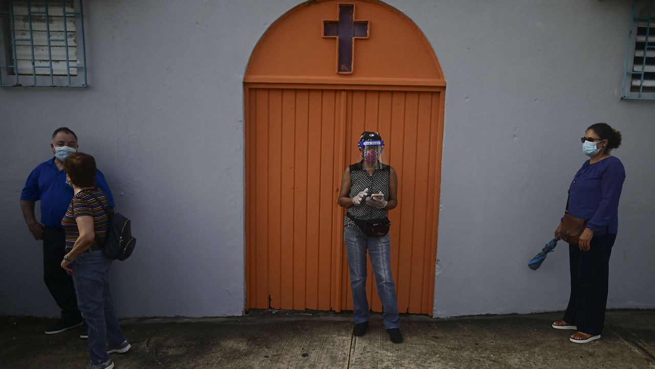 People practice social distancing as they wait in line to vote for general elections outside a church in San Juan, Puerto Rico, on Tuesday. (AP Photo/Carlos Giusti)