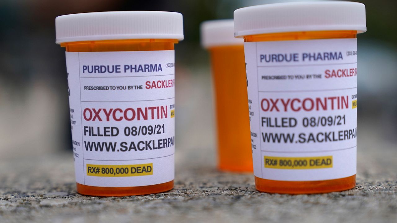 Fake pill bottles with messages about Purdue Pharma are displayed during a protest outside the courthouse in White Plains, N.Y. (AP Photo/Seth Wenig)