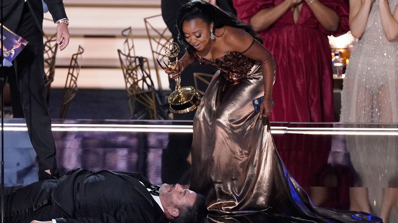 Quinta Brunson, right, winner of the Emmy for outstanding writing for a comedy series for "Abbott Elementary", checks on Jimmy Kimmel as he lays on stage at the 74th Primetime Emmy Awards on Monday, Sept. 12, 2022, at the Microsoft Theater in Los Angeles. (AP Photo/Mark Terrill)