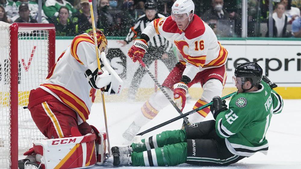 Dallas Stars center Radek Faksa (12) slides into Calgary Flames goaltender Jacob Markstrom, left, following a shot in the first period of Game 4 of an NHL hockey Stanley Cup first-round playoff series, Monday, May 9, 2022, in Dallas. Flames Nikita Zadorov is at center. (AP Photo/Tony Gutierrez)