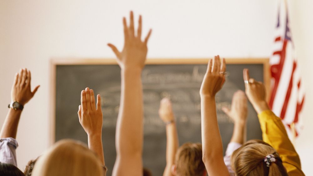 Students raising their hands in a classroom setting. (File)