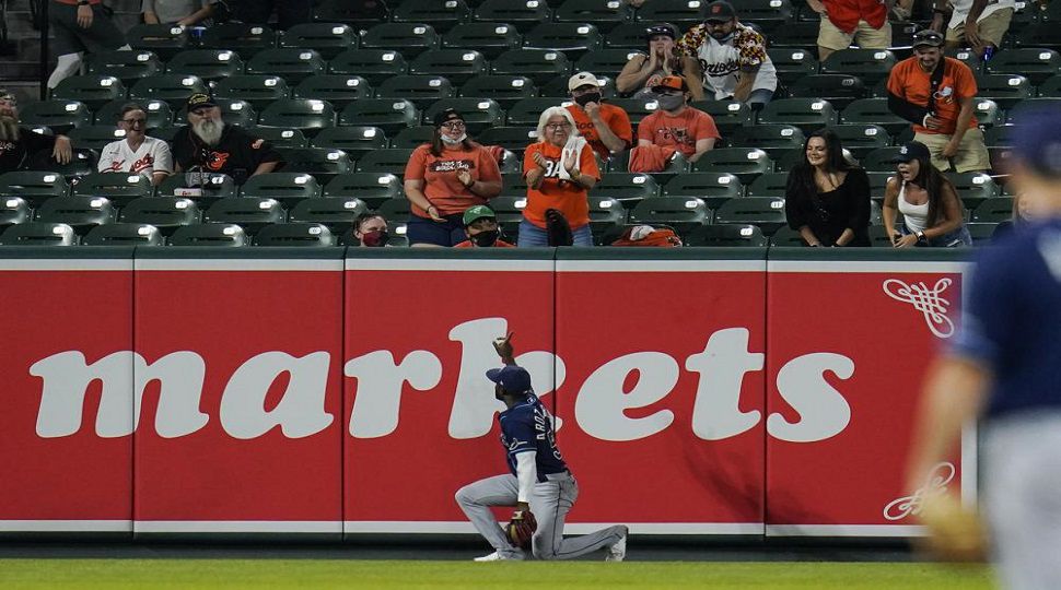 Tampa Bay Rays left fielder Randy Arozarena, bottom, gestures toward spectators after he robbed a home run ball hit by Baltimore Orioles' Pat Valaika during the sixth inning of a baseball game, Wednesday, May 19, 2021, in Baltimore. (AP Photo/Julio Cortez)