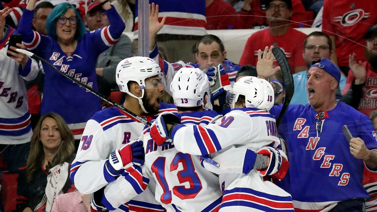 New York Rangers left wing Alexis Lafrenière (13) celebrates his goal against the Carolina Hurricanes with defenseman K'Andre Miller (79) and left wing Artemi Panarin (10) during the third period in Game 3 of an NHL hockey Stanley Cup second-round playoff series Thursday, May 9, 2024, in Raleigh, N.C. (AP Photo/Chris Seward)