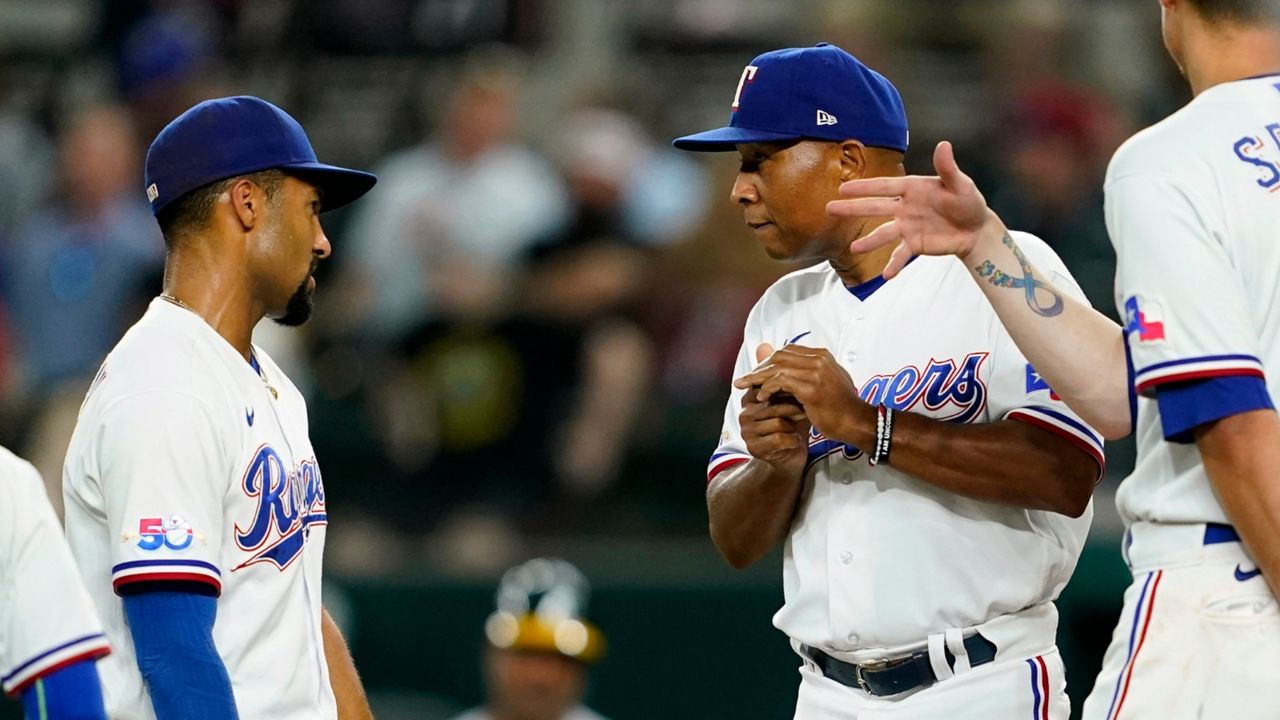 Texas Rangers' Marcus Semien, left, and Corey Seager, right, talk with interim manager Tony Beasley, center, on the mound after Beasley pulled starting pitcher Kohei Arihara in the sixth inning of a baseball game in Arlington, Texas, Tuesday, Aug. 16, 2022. (AP Photo/Tony Gutierrez)